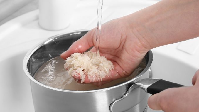 Woman rinsing rice in saucepan under running water